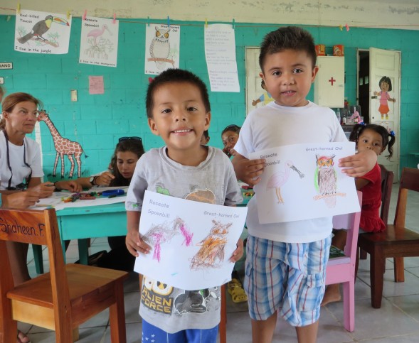 Two preschool students proudly show off their drawings